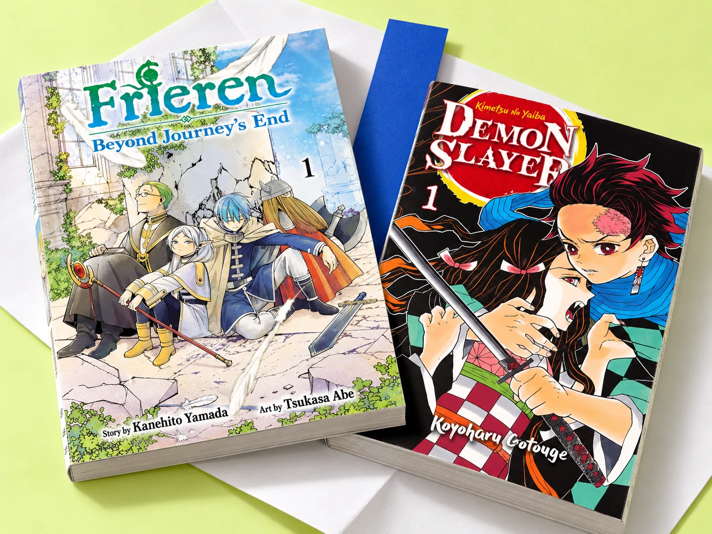 Frieren e Demon Slayer, volume 1, lado a lado sobre papel
